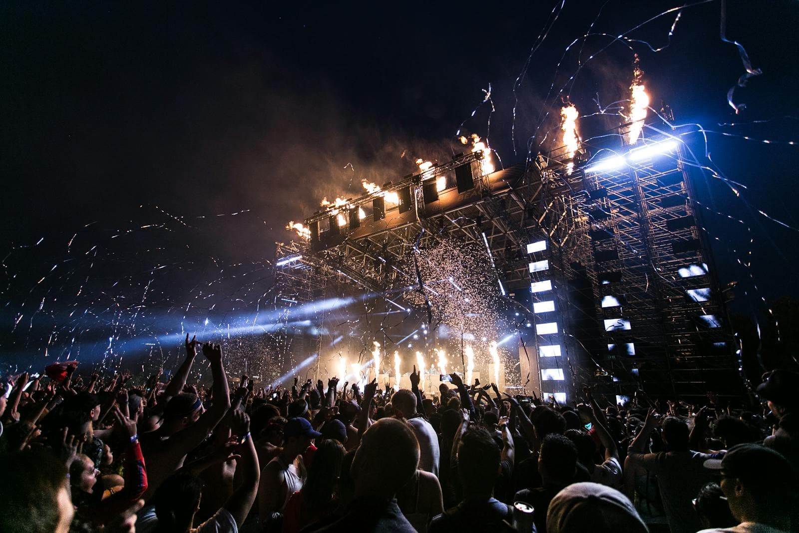 Audience at an indoor concert with magenta and blue stage wash lighting